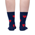 Flatlay image of a pair of red crew socks with maroon fuzzy hearts.