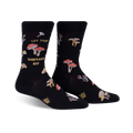 Pair of black crew socks featuring a whimsical mushroom design and the phrase 'Let That Shiitake Go'.  Red and gold mushroom illustrations scattered across the socks.