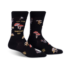 Pair of black crew socks featuring a whimsical mushroom design and the phrase 'Let That Shiitake Go'.  Red and gold mushroom illustrations scattered across the socks.