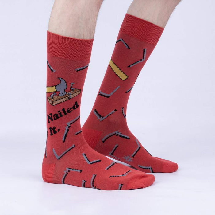 A pair of red socks with a pattern of hammers and nails. The socks are shown from the back.