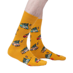 Lifestyle shot of model wearing mustard yellow crew socks featuring cars carrying Christmas trees.