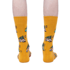 Rear view of mustard yellow crew socks with Christmas tree-hauling car pattern.