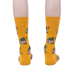 Rear view of mustard yellow crew socks with Christmas tree-hauling car pattern.