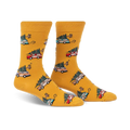 Pair of mustard yellow crew socks with a repeating pattern of cartoon cars carrying Christmas trees. 
