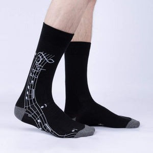 A pair of black socks with a clarinet printed on the back in white.