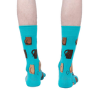 Back view of a pair of teal 'Kiss My' socks on a person's legs.