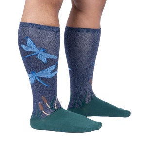 Lifestyle shot of model wearing a pair of teal and navy blue knee-high socks with a dragonfly design.