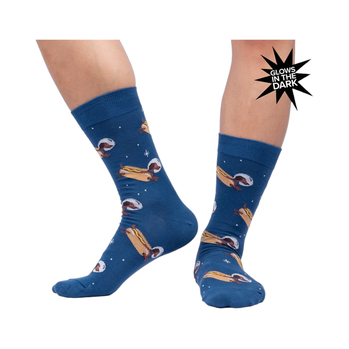 Lifestyle shot of a person wearing the 'Weiner Dogs, In Space!' socks, showcasing the glow-in-the-dark effect.