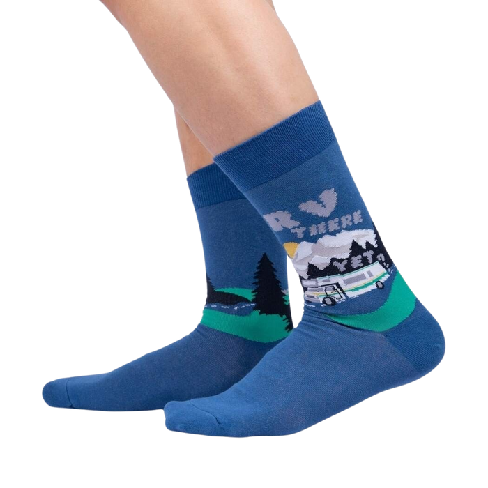 A pair of blue socks with a pattern of a camper van driving through a forest at night.