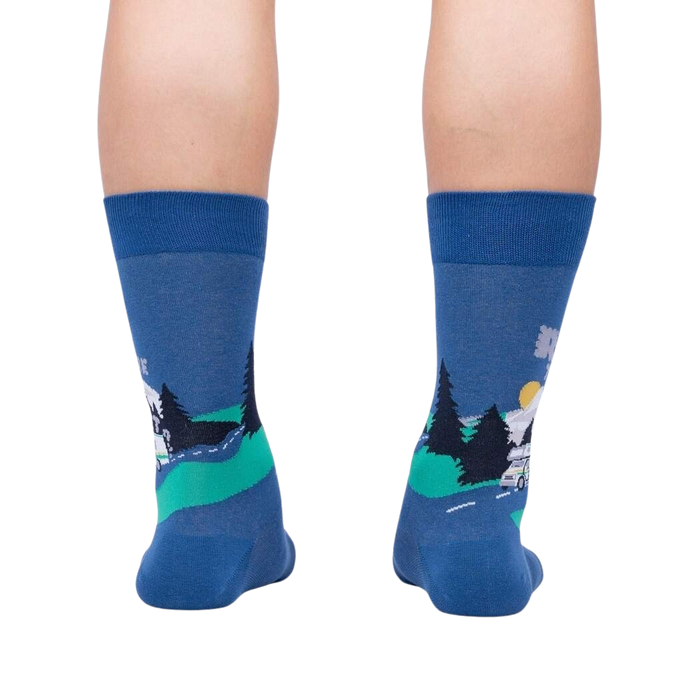 A pair of blue socks with a pattern of a camper van driving through a forest at night.