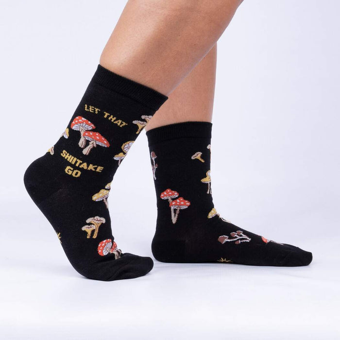 A pair of black socks with a pattern of different types of mushrooms on them. The socks are mid-calf length and the mushrooms are in a variety of colors including red, orange, yellow, and white.