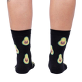 Back view of the same socks shown on a person's legs.  The avocado-cat design is clearly visible from behind.