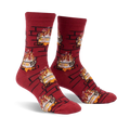 Pair of crew socks in burgundy with a repeating pattern of burning yule logs in a brick fireplace. 