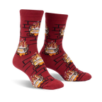 Pair of crew socks in burgundy with a repeating pattern of burning yule logs in a brick fireplace. 