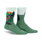 Crew socks in green and mint green featuring a cartoon bear in a forest scene. The bear holds a sign that says 'That's Shady'.