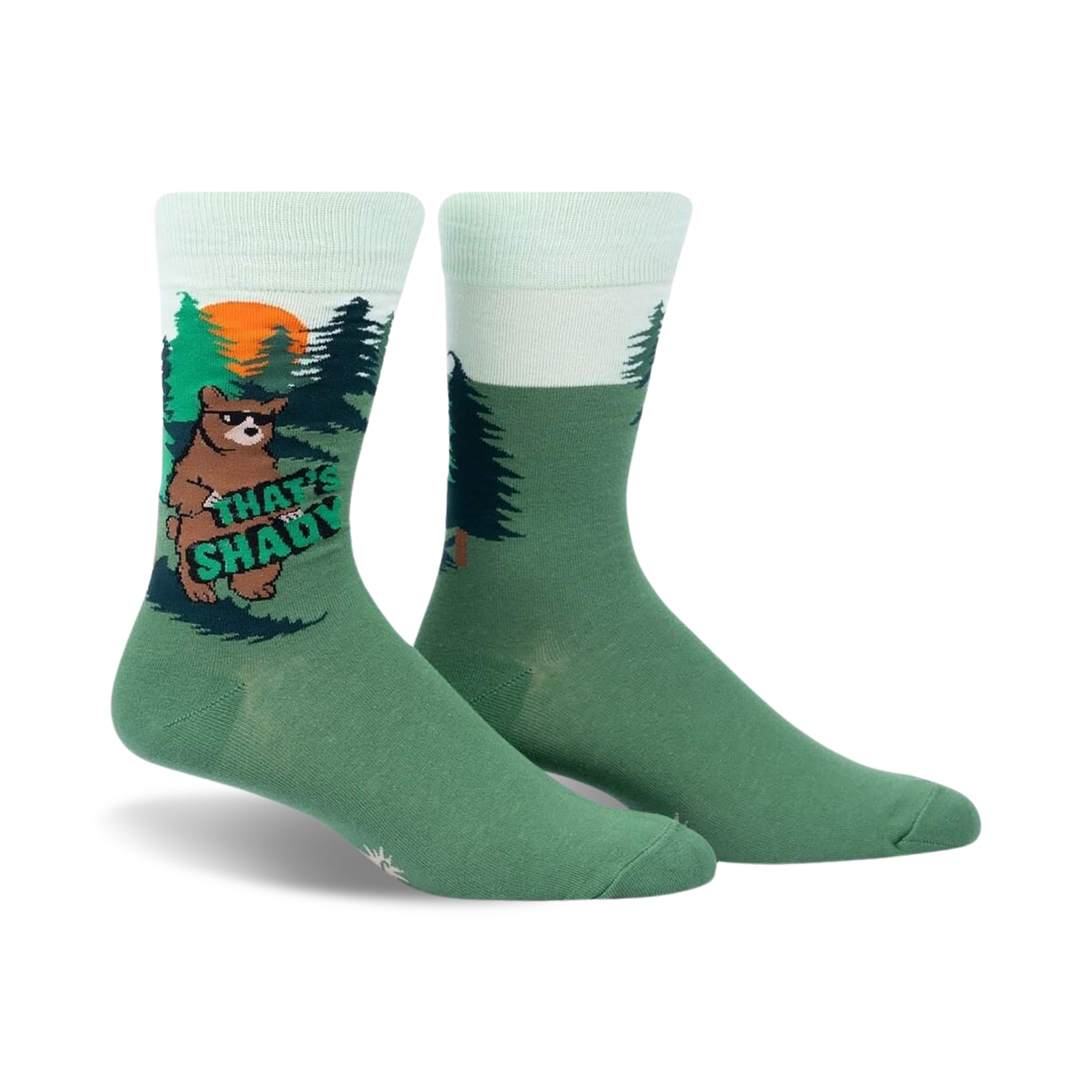 Crew socks in green and mint green featuring a cartoon bear in a forest scene. The bear holds a sign that says 'That's Shady'.