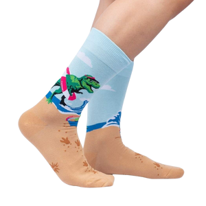 A pair of light blue socks with a pattern of pink flamingos wearing Santa hats on a sandy beach with the ocean in the background.