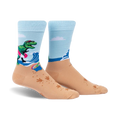 Crew socks in light blue and tan. Design features a T-Rex on a surfboard at the beach with wave and footprint details.