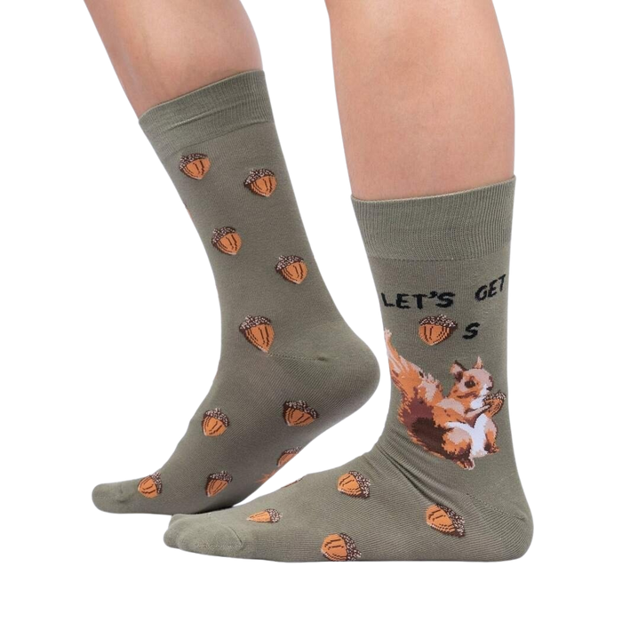 A pair of green socks with a pattern of squirrels holding acorns. The socks have the text 