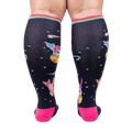 Rear view of Space Cat knee-high socks on a person's legs.  Full view of the sock pattern and bright pink heel.