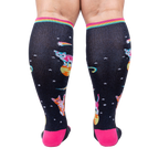 Rear view of Space Cat knee-high socks on a person's legs.  Full view of the sock pattern and bright pink heel.