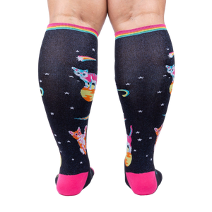 Rear view of Space Cat knee-high socks on a person's legs.  Full view of the sock pattern and bright pink heel.