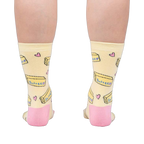 Rear view of the socks on a person's legs, highlighting the pink heel and toe details against the pastel yellow.