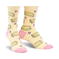 Pair of pastel yellow crew socks with a repeating pattern of butter pats and pink hearts. Pink accents on the heel and toe.