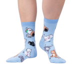 Lifestyle shot of a person wearing the light blue crew socks with cat and pill bottle design.