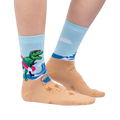 Lifestyle shot of Dinos Gone Wild socks on a person's feet, showcasing the beach-themed design.