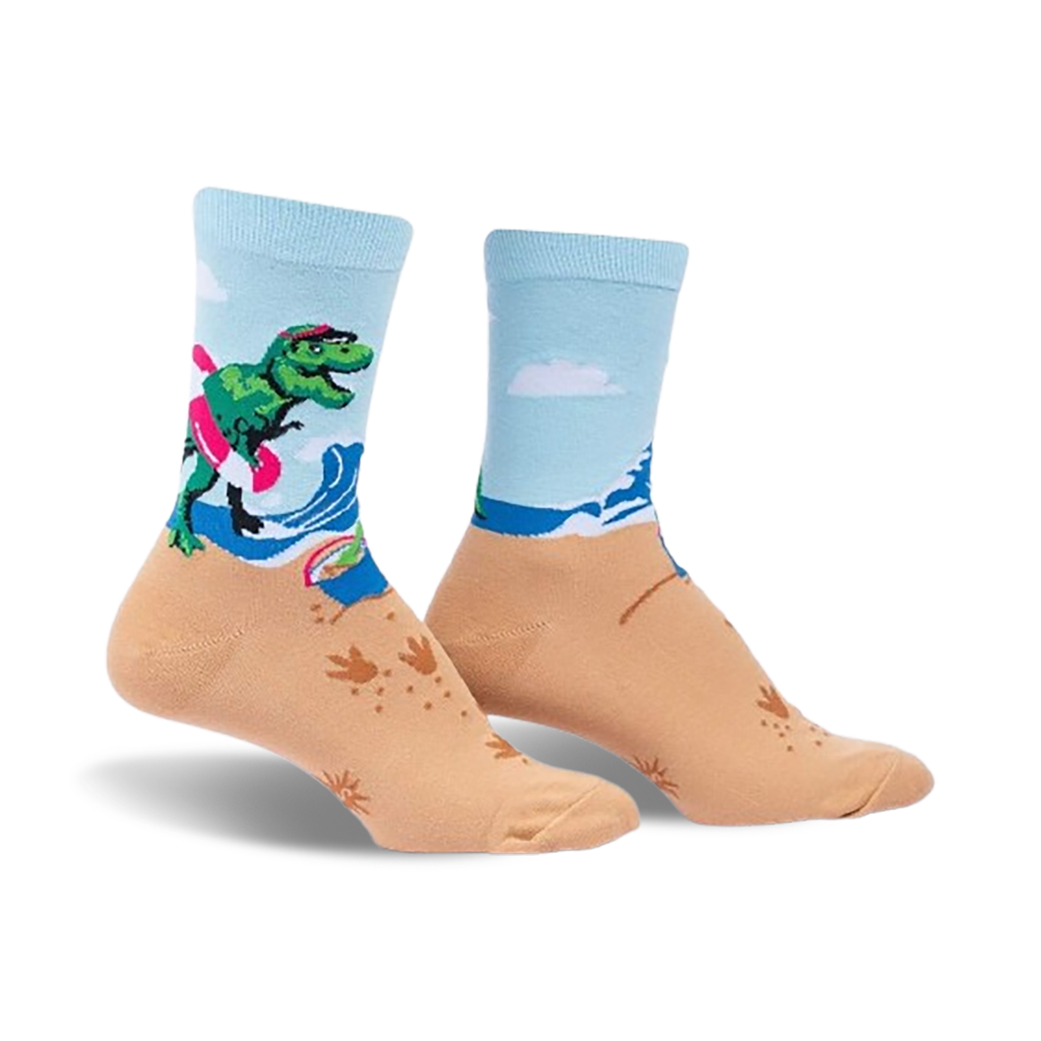 A pair of crew socks showcasing a T-Rex surfing on a beach.  The socks are light blue and tan with green, pink, and white accents.