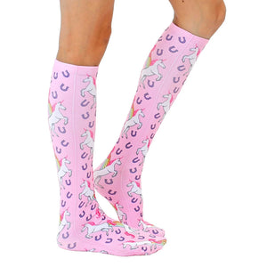 A pair of pink knee-high socks with a pattern of white unicorns with rainbow manes and tails leaping over golden horseshoes.