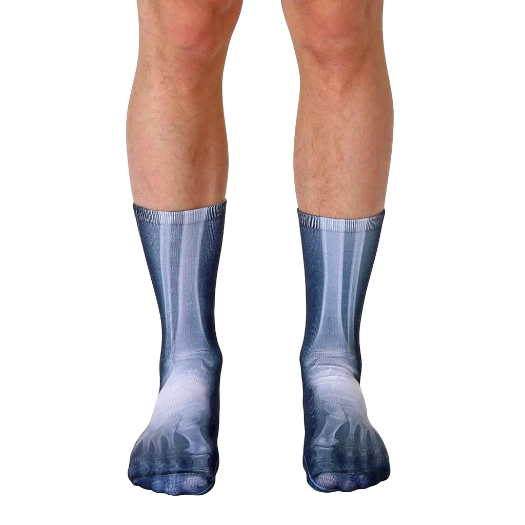 Pair of crew socks showcasing a grayscale x-ray image of feet and lower legs.  The socks are mainly dark gray with lighter gray bone details. [lf]