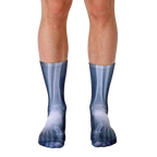 Pair of crew socks showcasing a grayscale x-ray image of feet and lower legs.  The socks are mainly dark gray with lighter gray bone details. [lf]