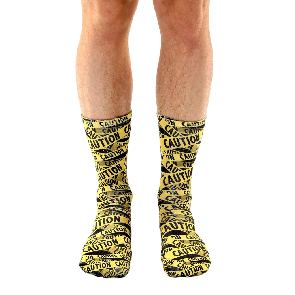 Lifestyle shot of a person's legs wearing the 'Caution' socks. The socks are the main focus, against a white background. [lf]