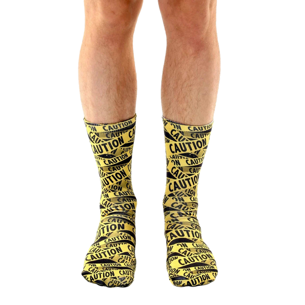Lifestyle shot of a person's legs wearing the 'Caution' socks. The socks are the main focus, against a white background. [lf]