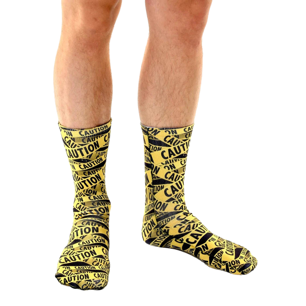 Another lifestyle shot of a person wearing the 'Caution' socks. Shows a different angle of the socks on the model's legs. [lf]