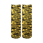 Pair of crew socks with a repeating caution tape pattern in black and yellow.  The design features the word 'CAUTION' printed on the tape.