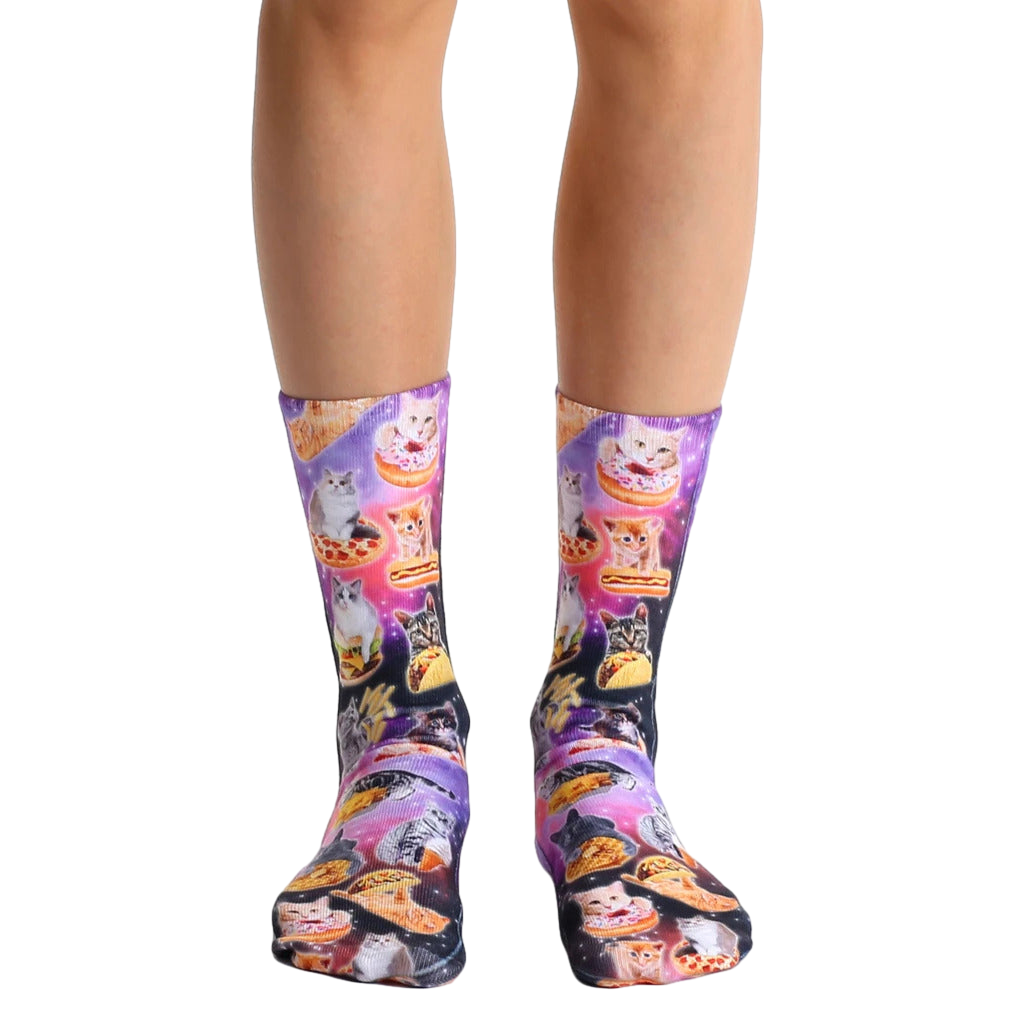 Crew socks with a vibrant purple, pink, and black space-themed design.  Multiple cats enjoying various foods like pizza and tacos are featured. [lf]