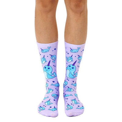 blue and white cartoon narwhals swim in a purple sea on these women's crew socks  