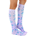 Lifestyle shot: Model wearing a pair of lavender knee-high narwhal socks. [lf]