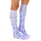 Lifestyle shot: Model wearing a pair of lavender knee-high narwhal socks. [lf]