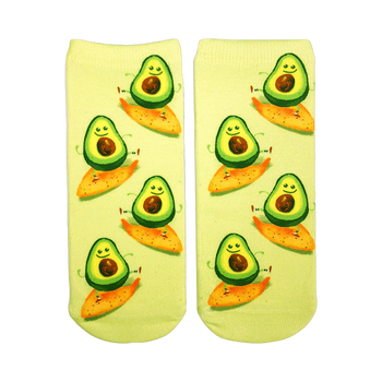 Pair of ankle socks on white background. Light green background with cartoon avocados riding orange tortilla chips. 