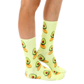 Lifestyle shot showing the Surfing Avocado socks on a person's legs.  The socks' pastel yellow and avocado design is clearly visible. [lf]