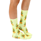 Lifestyle shot showing the Surfing Avocado socks on a person's legs.  The socks' pastel yellow and avocado design is clearly visible. [lf]
