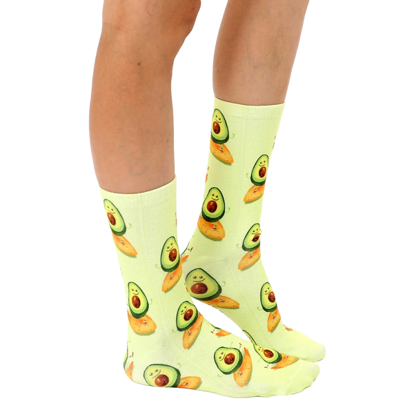 Lifestyle shot showing the Surfing Avocado socks on a person's legs.  The socks' pastel yellow and avocado design is clearly visible. [lf]