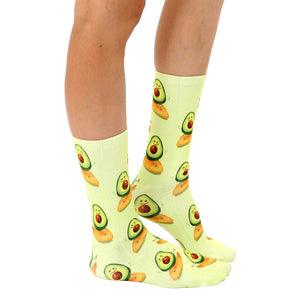 A pair of light green socks with an all-over pattern of cartoon avocados on toast.