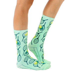 A pair of mint green socks with a pattern of tennis rackets and tennis balls.