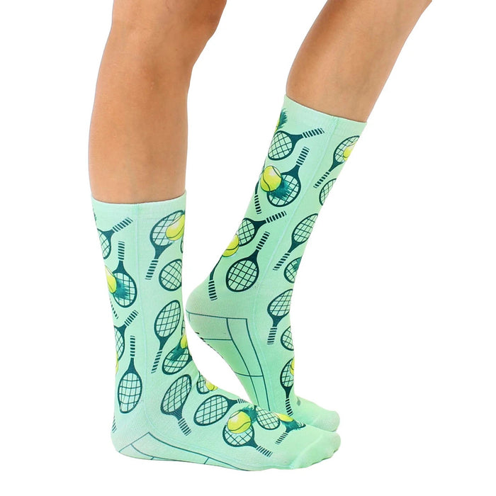 A pair of mint green socks with a pattern of tennis rackets and tennis balls.