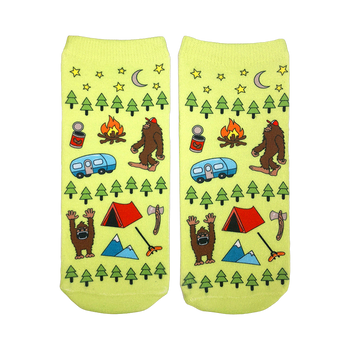 A pair of lime green ankle socks with a fun camping design. The pattern includes Bigfoot, a camper, tent, trees, and stars.